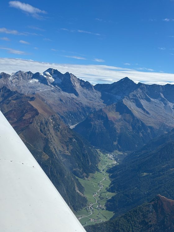 A mountain valley with peaks and part of a wing, photographed from the air