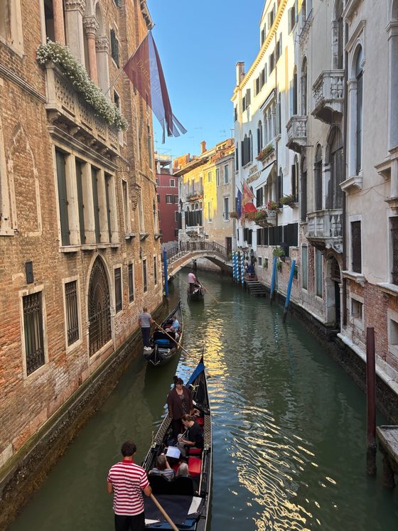 Several gondolas in a narrow canal between Venetian houses