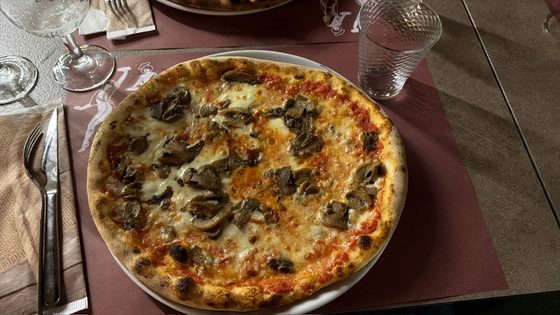Italian pizza with mushrooms on a laid restaurant table